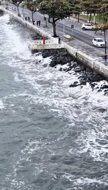 Ondas fortes atingem estrutura próxima à orla durante mar agitado na Baixada Santista